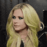 a close up of a woman with long blonde hair and green highlights .