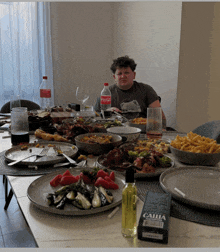 a man sits at a table with plates of food and a coca cola bottle