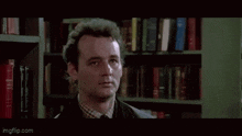 a man is standing in front of a bookshelf with the words `` so what do we do '' written on it .