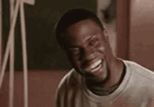 a man is laughing and looking at the camera while wearing a white shirt .