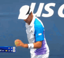 a man in a blue and purple shirt is swinging a tennis racket .