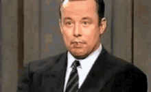 a man in a suit and tie has a cigarette in his mouth .
