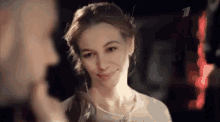 a woman is smiling and looking at a man 's face .