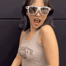 a woman wearing sunglasses and a tank top that says sentite on it