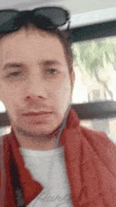 a man wearing sunglasses and a red vest has a white shirt that says ' ralph lauren ' on it