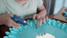 a person is using a glue gun to glue plastic spoons on a table .