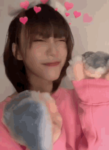 a girl wearing a pink sweater and a headband with hearts on it