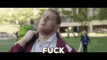 a man with a beard is holding a soccer ball over his shoulder and saying fuck .