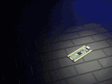 a small electronic device is laying on a black tiled floor
