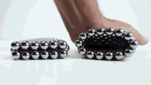 a person is playing with a bunch of metal balls on a table