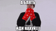 a man in a black sweater is holding a pair of red mittens with white snowflakes