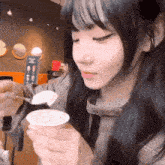 a girl is eating yogurt with a spoon in a cup