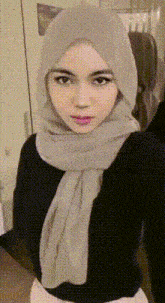 a woman wearing a hijab and a black shirt takes a selfie