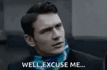 a man in a suit and scarf is saying well , excuse me .