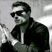 a black and white photo of a man wearing sunglasses .