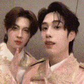 two young men are posing for a picture together . one of the men is wearing a pink jacket .