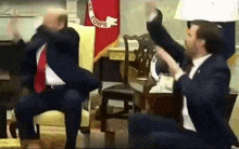 a man in a suit and tie is sitting on a chair while another man throws papers in the air .