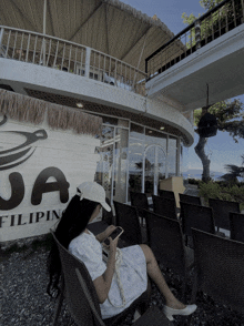 a woman sits in front of a sign that says " ja filipino "