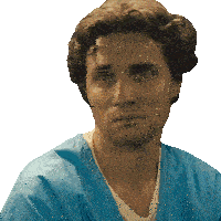 a man in a blue scrub top looks at the camera with a serious look on his face