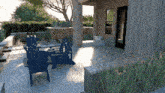 two blue lawn chairs sit on a patio outside of a house