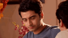 a man in a blue shirt is looking down at something while another man looks on .