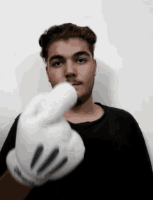 a young man wearing a mickey mouse glove is pointing at the camera