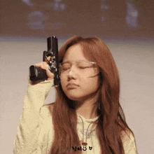 a girl wearing glasses is holding a gun over her head