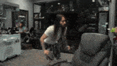 a man with long hair and a beard is sitting in a chair in a room with a claw machine in the background .