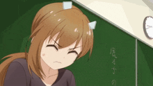 a girl with horns on her head sits in front of a blackboard with chinese writing