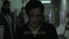 a man in a black shirt with apex predator written on the bottom right