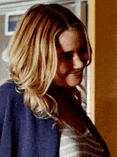 a woman wearing a striped shirt and a blue jacket smiles