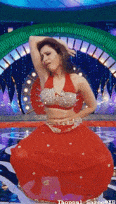 a woman in a red dress is dancing on a stage with the words thoppul saree xb written below her