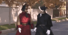 a man in a red dress and a woman in a black dress are walking down the street .