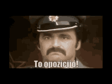 a man with a mustache is wearing a police hat and says to opozicijo