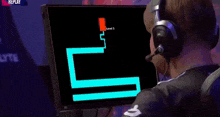 a man wearing headphones is looking at a scary face on a computer monitor