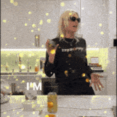 a woman in a black shirt that says i 'm is standing in a kitchen