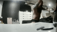 a man without a shirt is standing in a bedroom