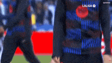a man wearing a black and blue shirt is standing on a red and blue field .