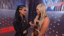 two female wrestlers are standing next to each other in front of a wall with a w on it