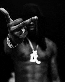 a black and white photo of a shirtless man making a middle finger gesture .