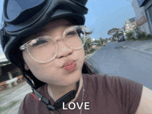 a woman wearing glasses and a helmet with the word love on her face