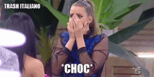 a woman is covering her face with her hands and the word choc is on the screen .