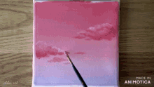 a painting of pink clouds is being painted on a canvas by chloe art
