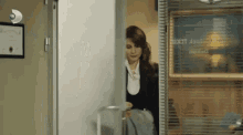 a woman is standing in a doorway in an office holding a briefcase .