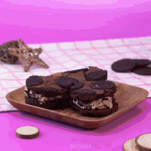 a wooden plate topped with oreos and brownies on a table