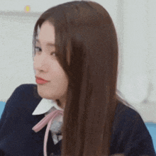 a close up of a woman 's face with long brown hair and a pink bow .