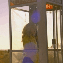 a woman is standing in a telephone booth that says telephone on it