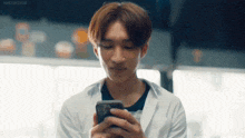a man in a white coat is looking at his cell phone .
