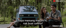 a man and a woman sitting in front of a blue van with the words saya memang macam ni nak buat camna