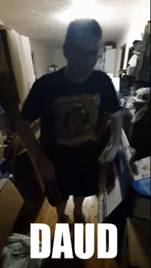 a man in a black shirt is standing in a messy room with the word daud written on the bottom